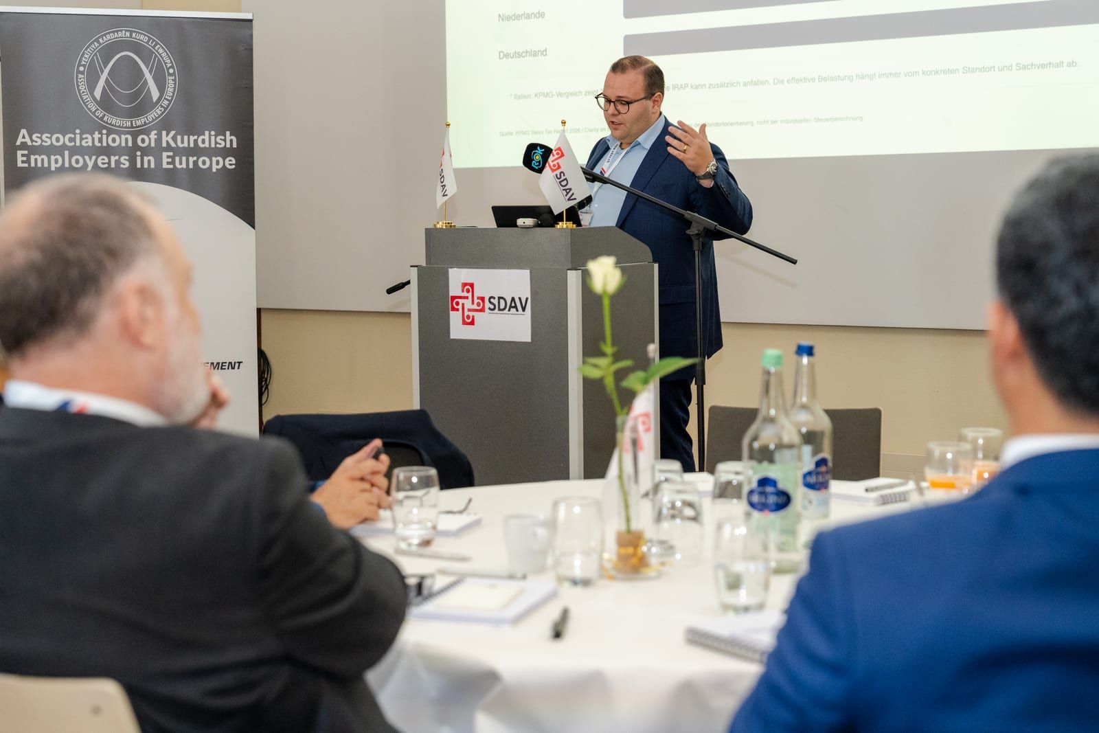 Jordi Alvarez, president of SDAV, gesturing at the lectern, guests at a round table in the foreground.