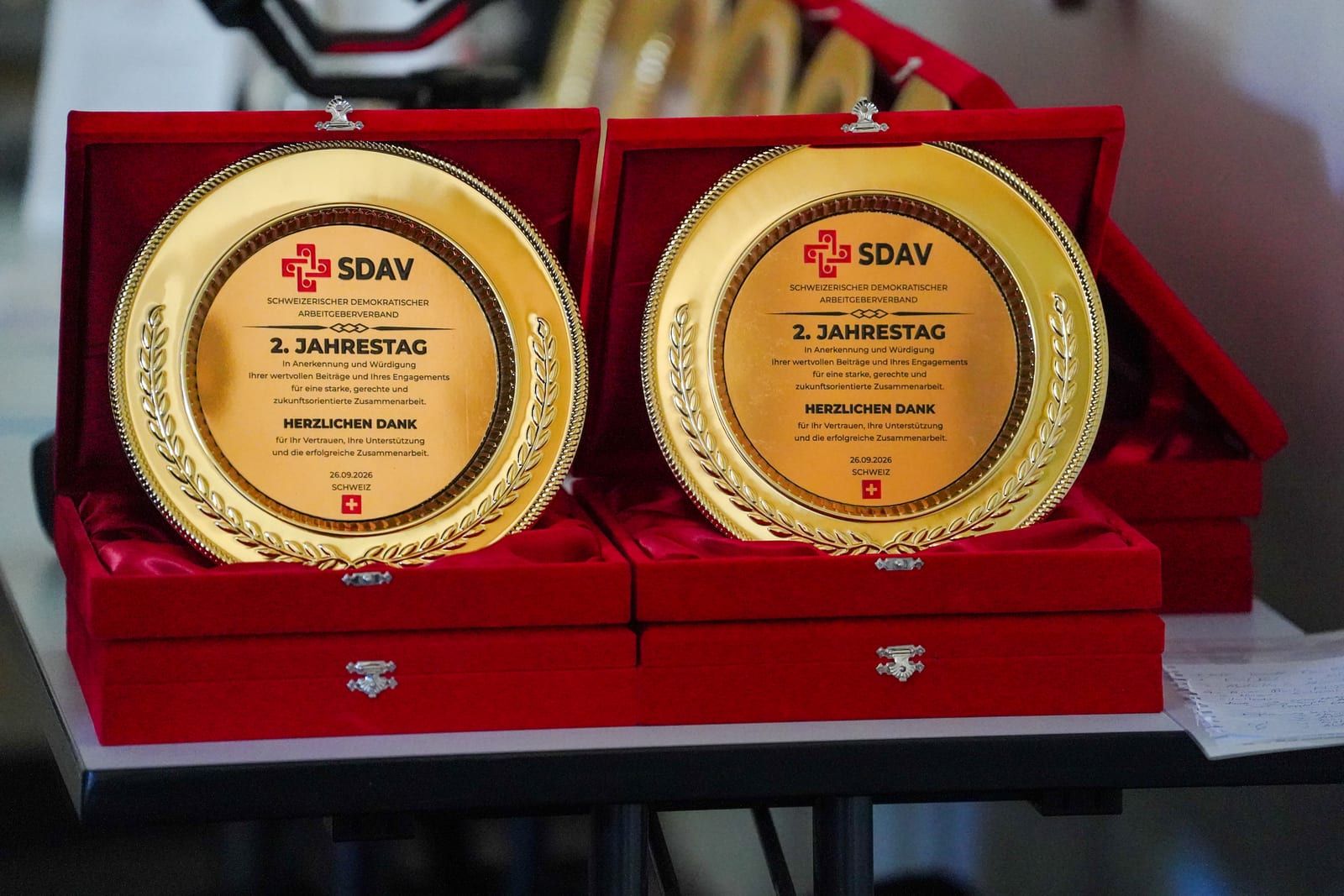 Two SDAV anniversary medallions in open red presentation boxes, engraved “2. Jahrestag – Herzlichen Dank”.